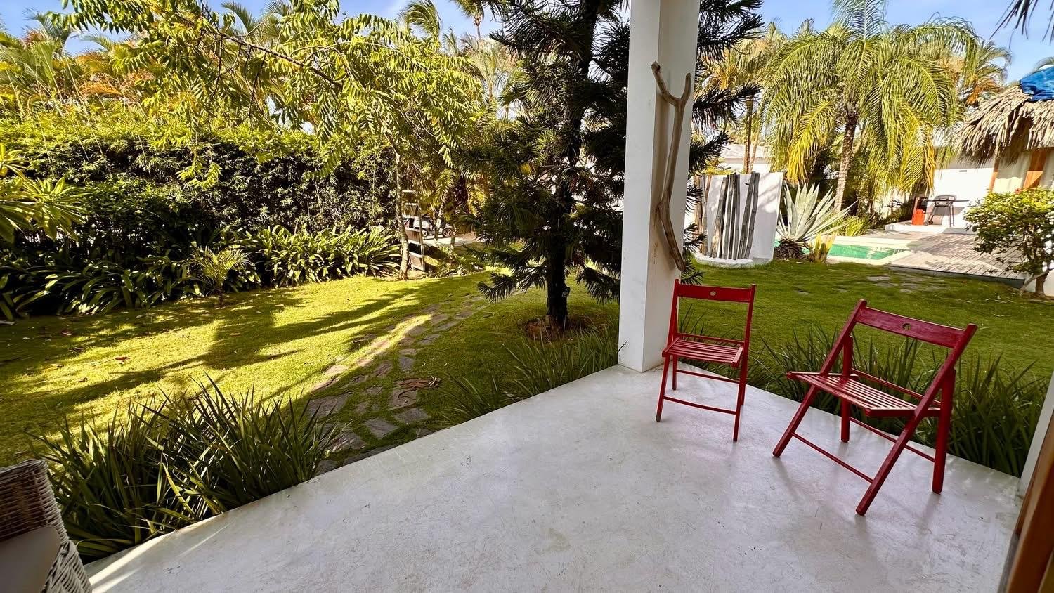 Porche con sillas rojas y jardín tropical