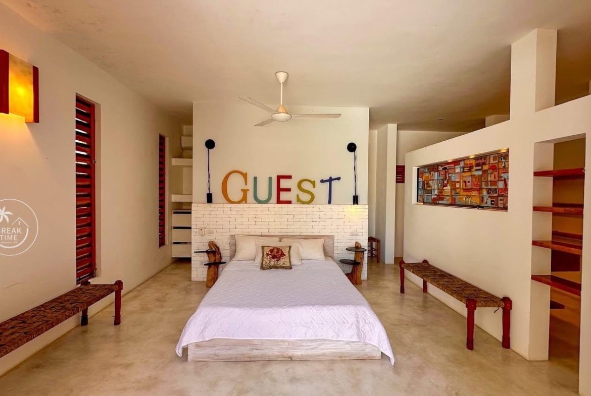 Dormitorio moderno con cama y letrero GUEST