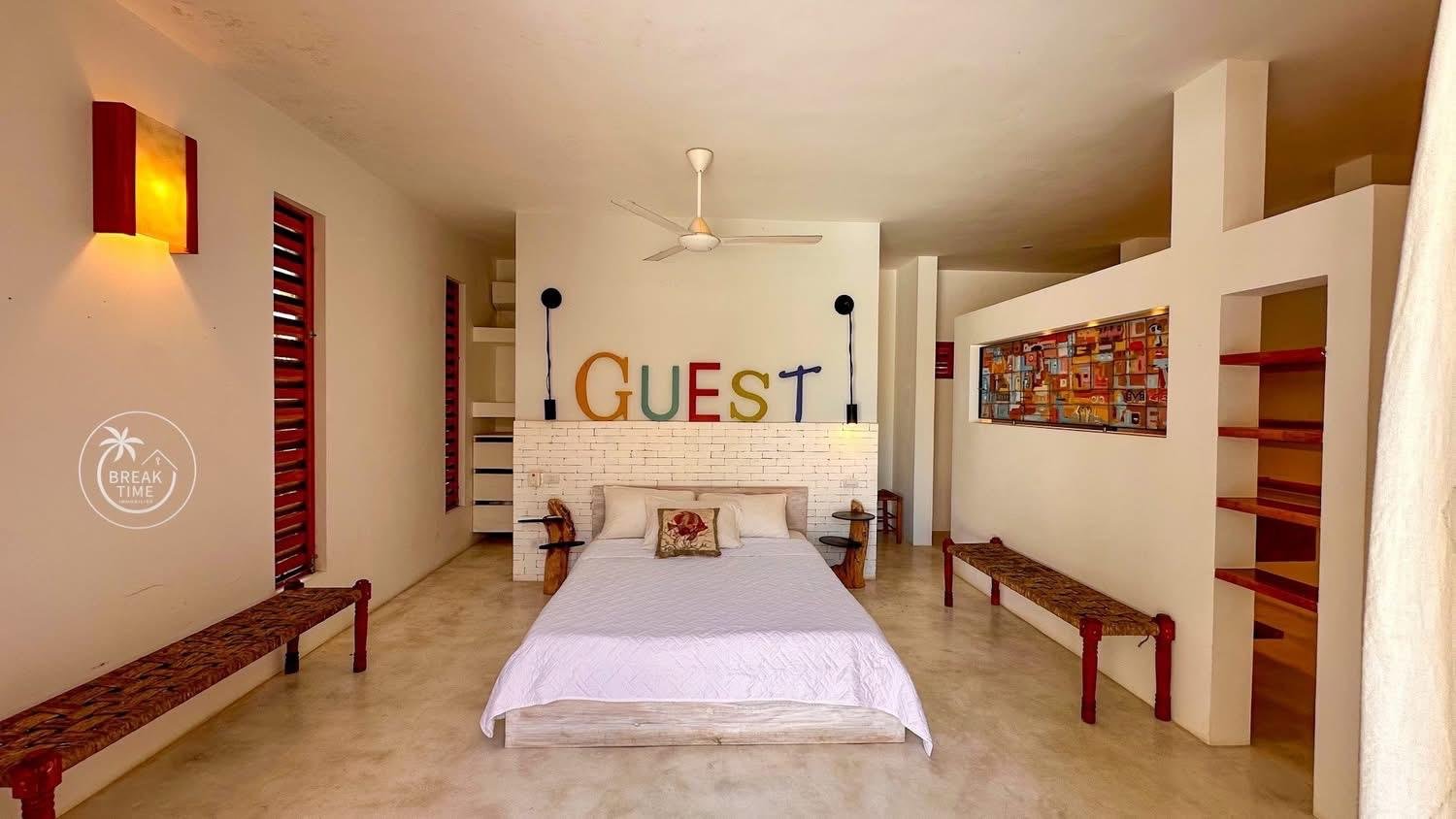 Dormitorio moderno con cama y letrero GUEST