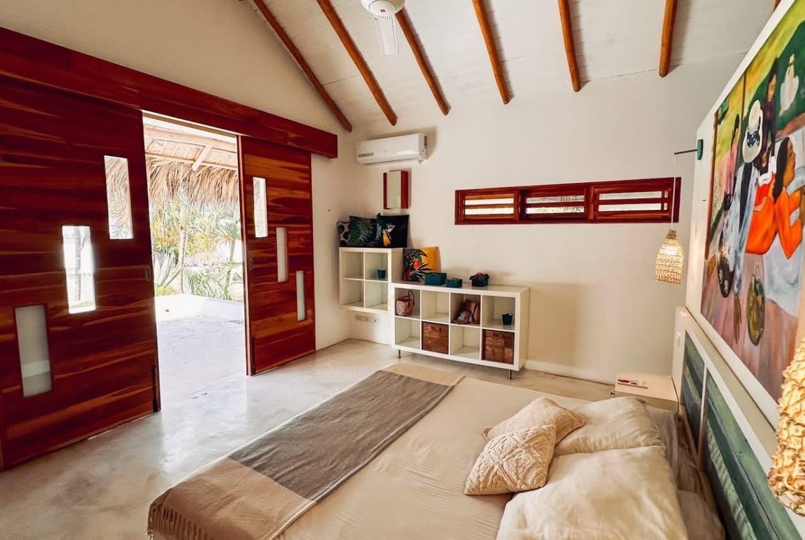 Dormitorio tropical moderno con puertas de madera abiertas