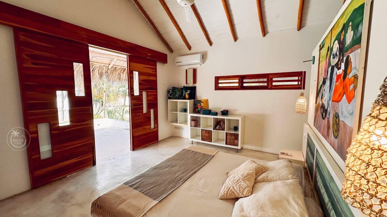 Dormitorio tropical moderno con puertas de madera abiertas