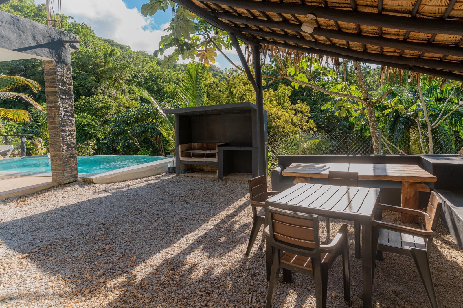 Terraza tropical con piscina, barbacoa y mesa exterior