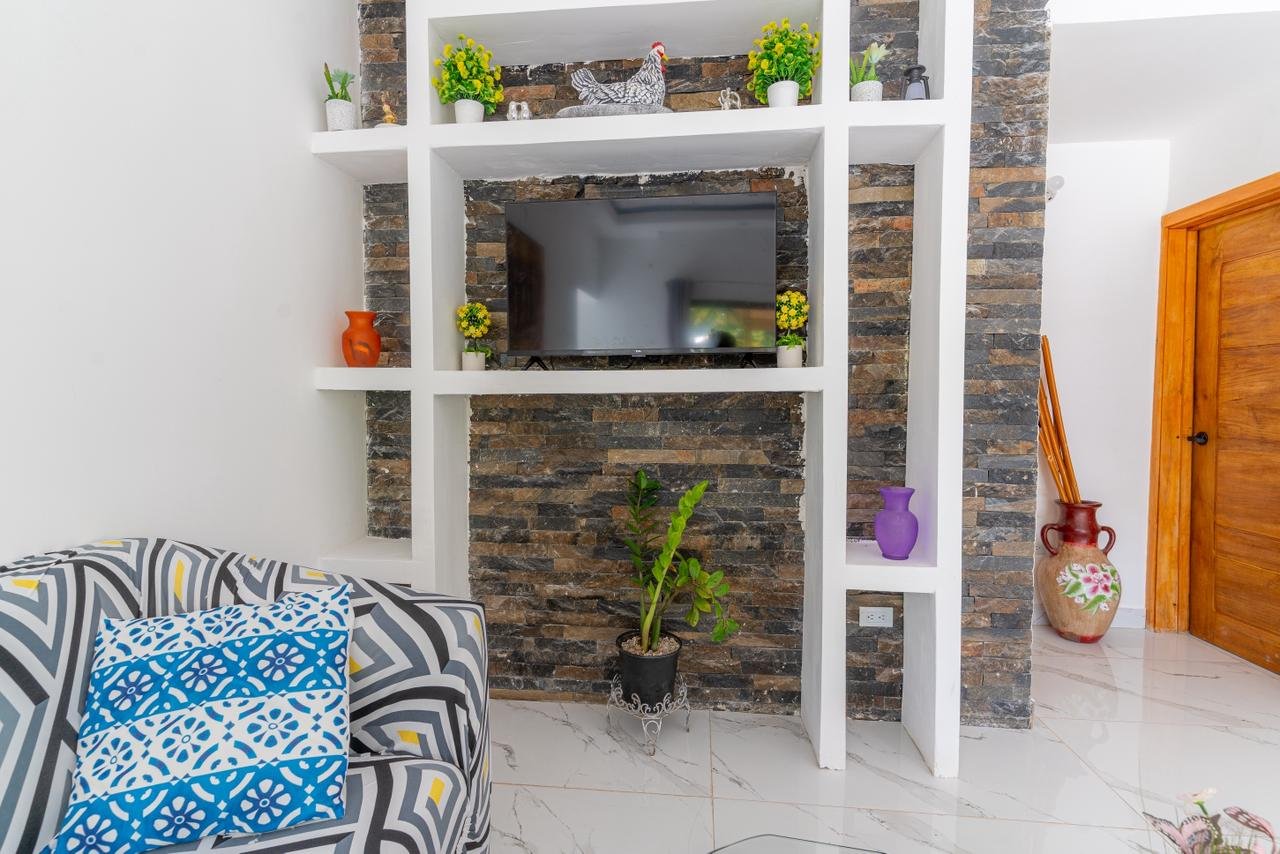 Salón moderno con pared de piedra y televisión