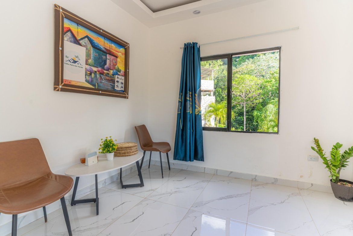 Sala luminosa con sillas y ventana al jardín