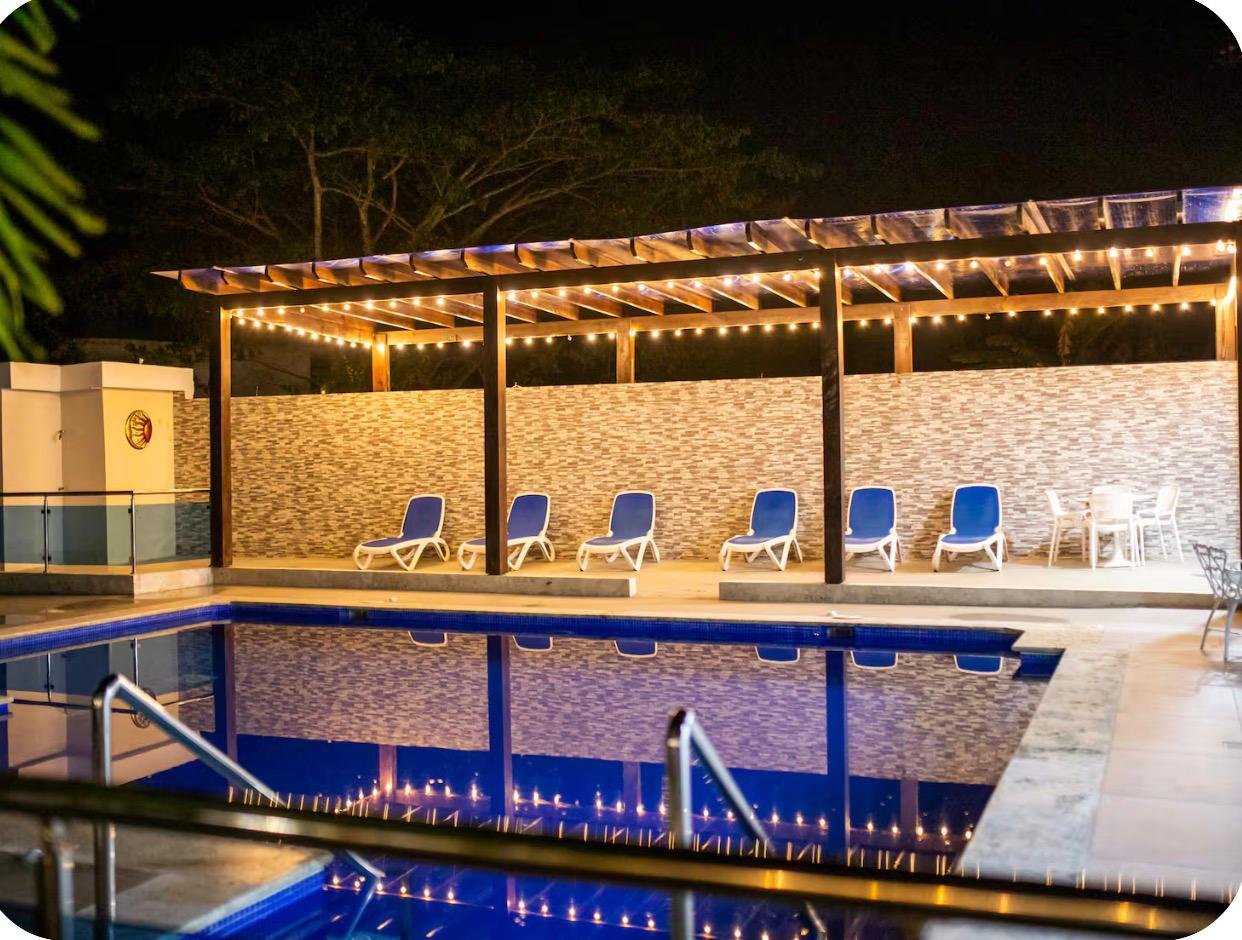 Piscina iluminada de noche con tumbonas azules
