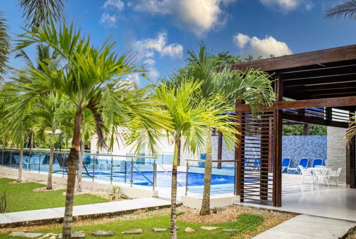 Piscina tropical con palmeras y pérgola moderna