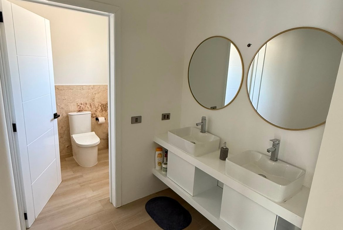Baño moderno con doble lavabo y espejos redondos