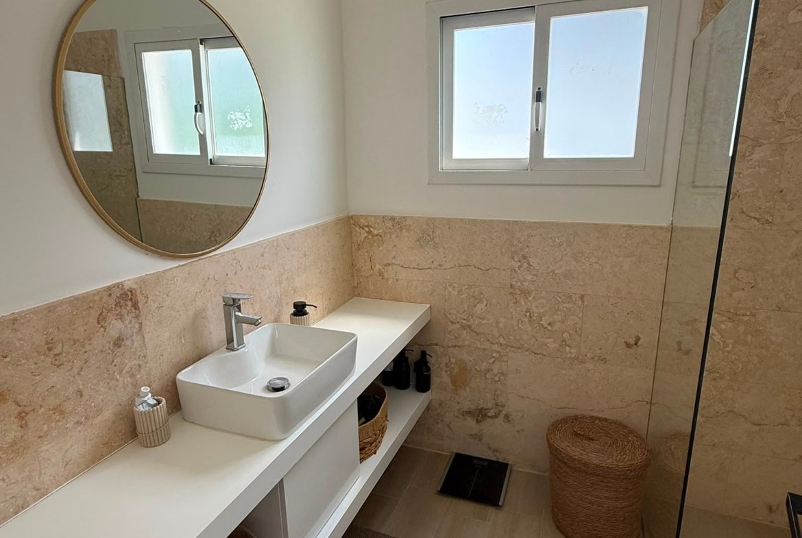 Baño moderno con lavabo y espejo redondo