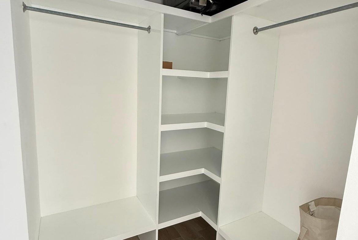 Vestidor blanco vacío con estanterías y barras