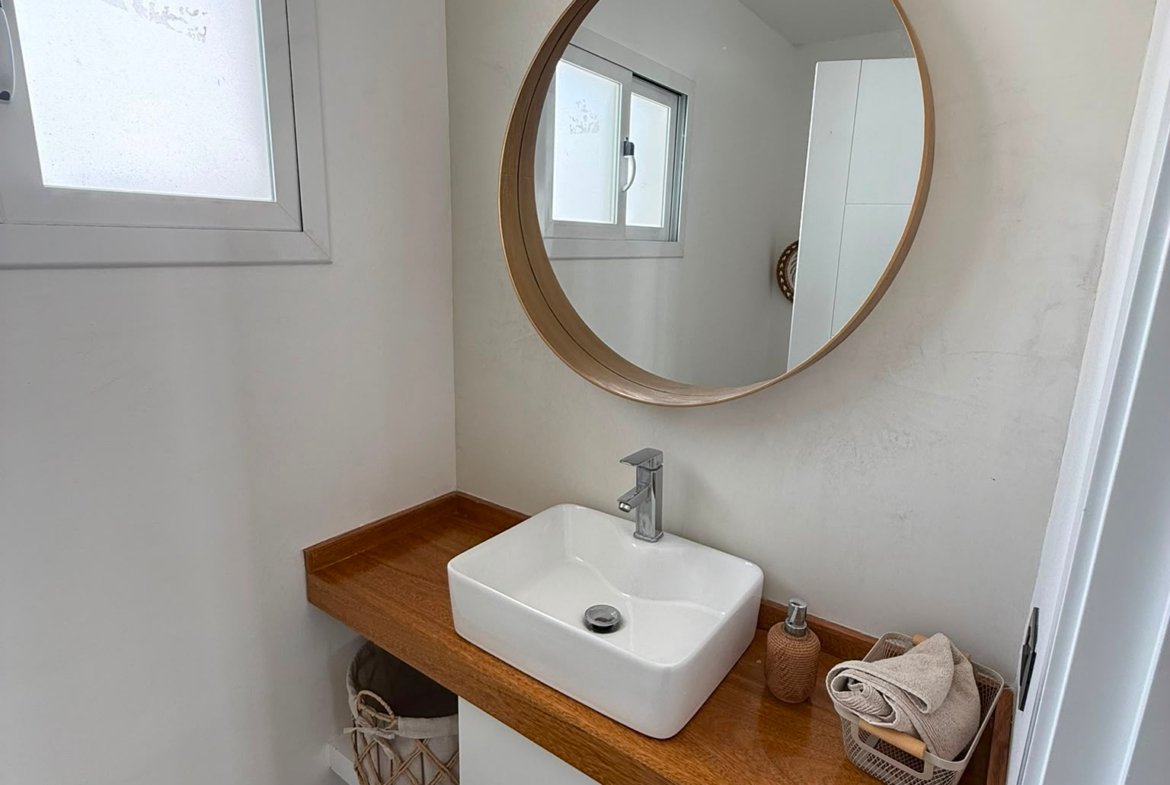 Baño pequeño con lavabo moderno y espejo redondo