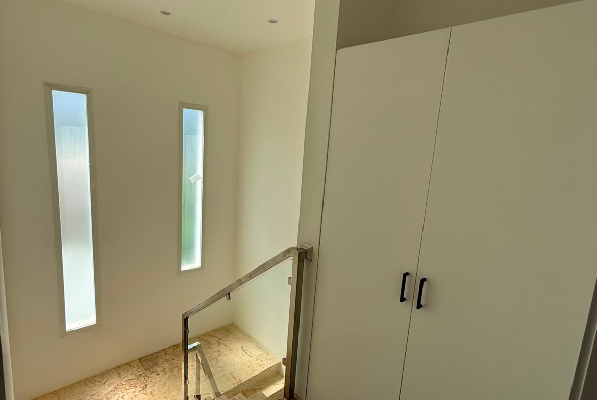 Escalera moderna con ventanales estrechos y armario blanco