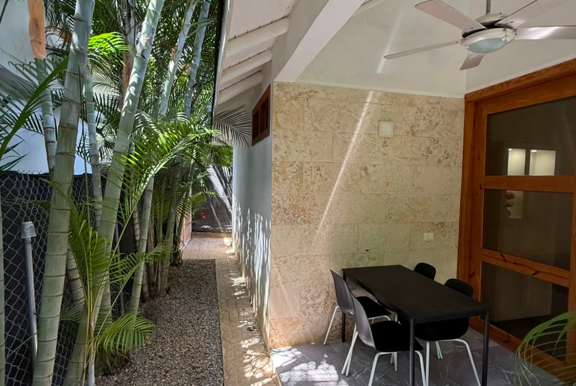 Patio estrecho con mesa y plantas tropicales