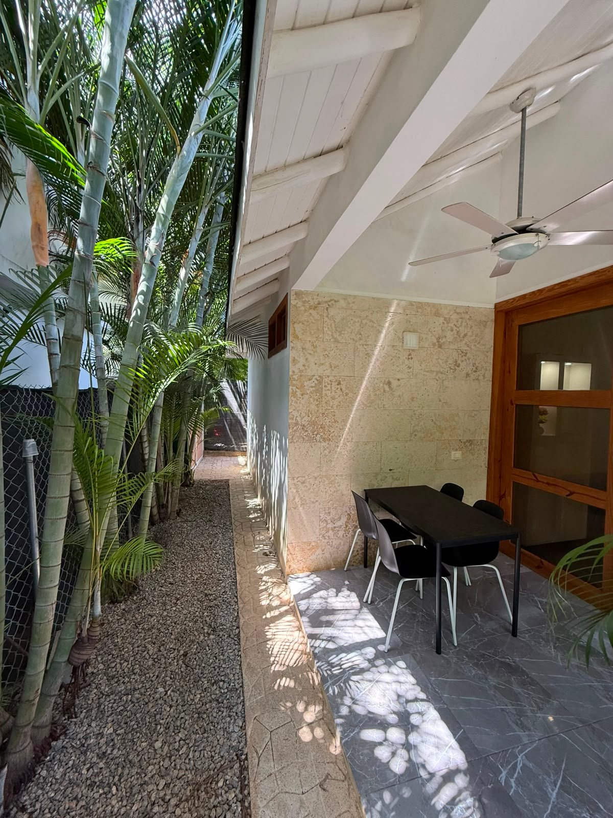 Patio estrecho con mesa y plantas tropicales