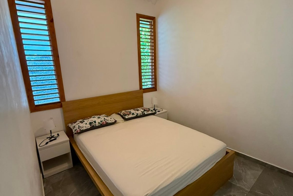 Dormitorio minimalista con cama doble y ventilador