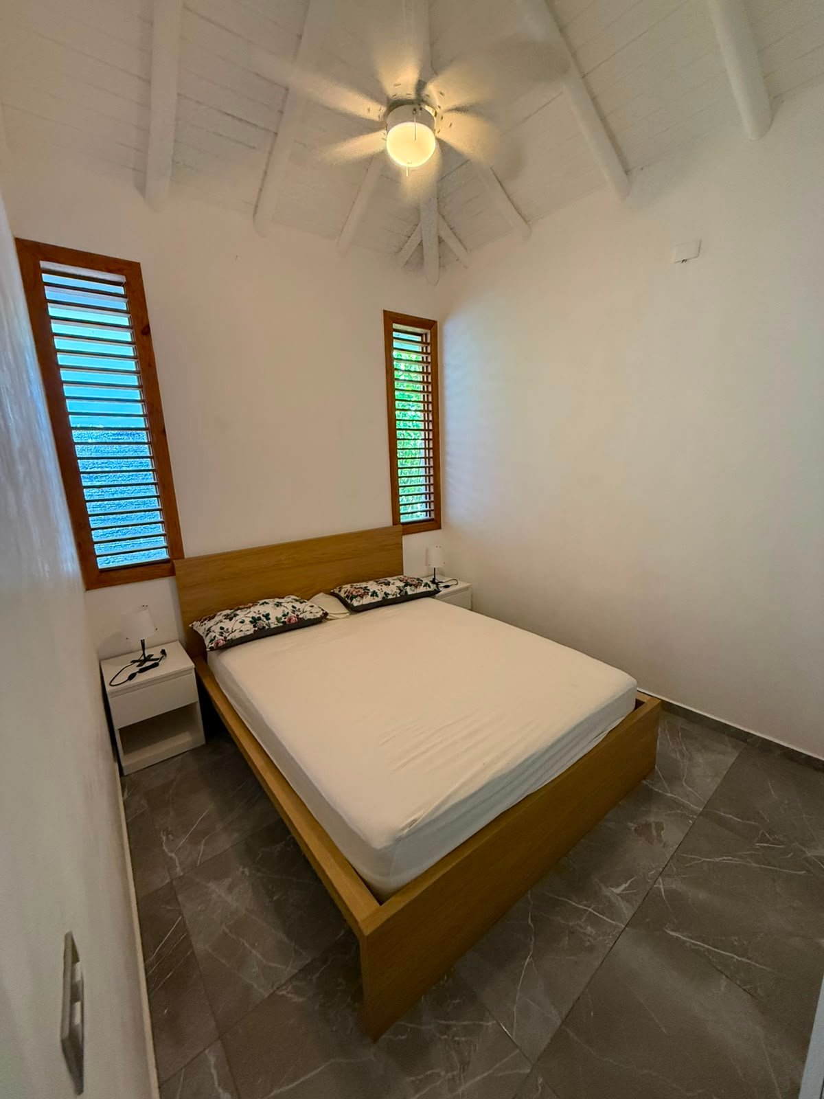 Dormitorio minimalista con cama doble y ventilador