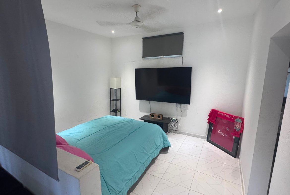 Dormitorio moderno con televisión y cama turquesa