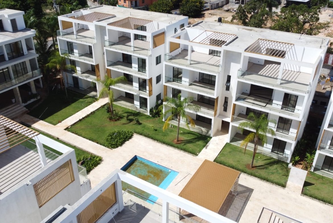 Complejo residencial moderno con piscina y jardines tropicales