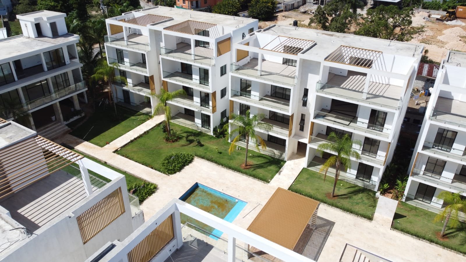 Complejo residencial moderno con piscina y jardines tropicales