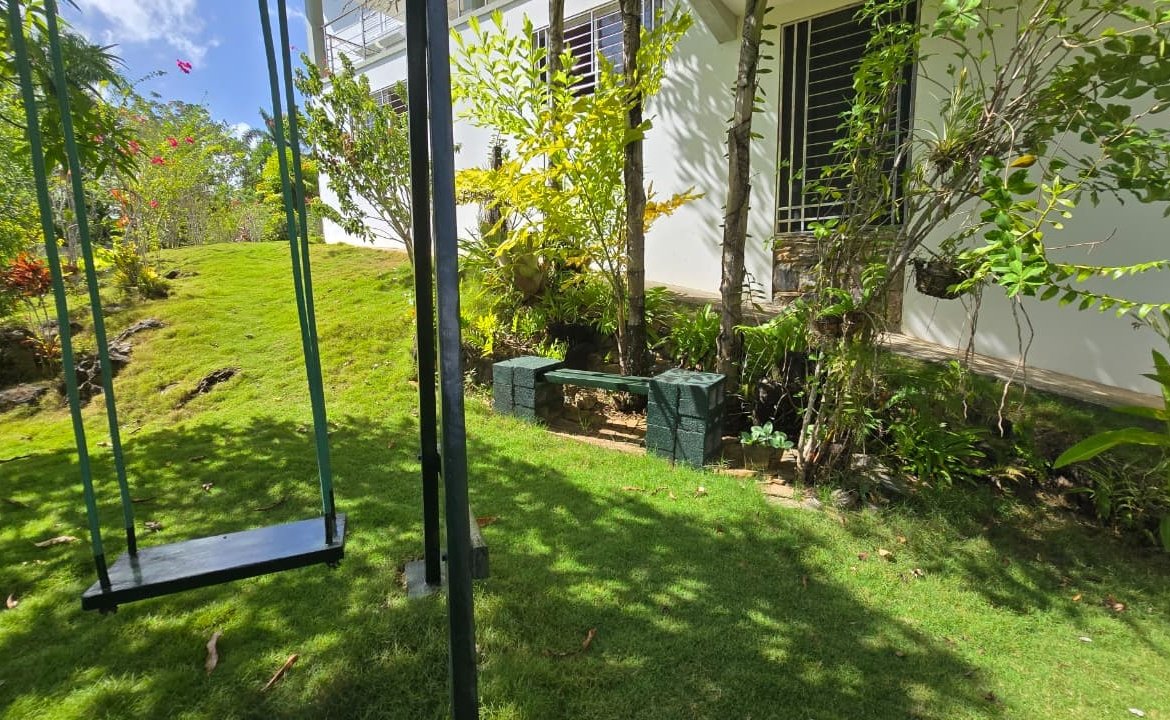 Columpio negro en jardín junto a una casa blanca