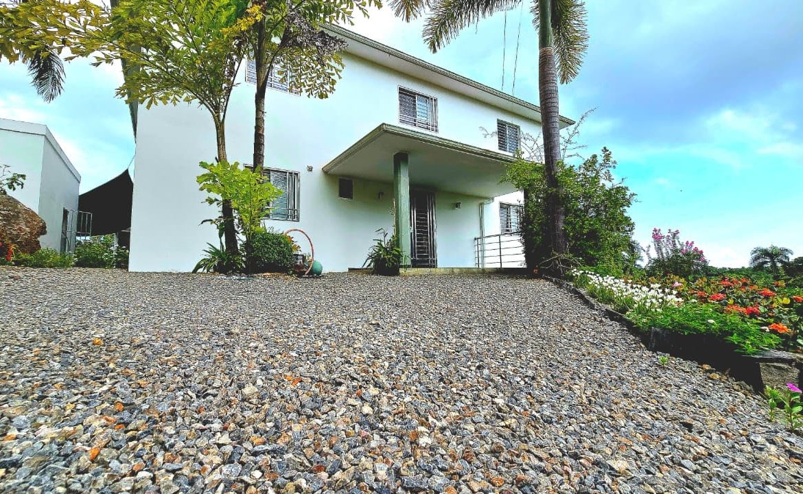 Casa blanca con jardín tropical y entrada de grava