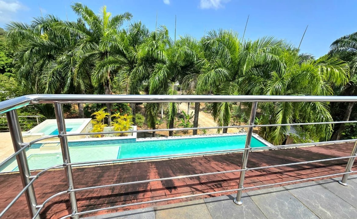 Piscina tropical vista desde terraza con barandilla metálica