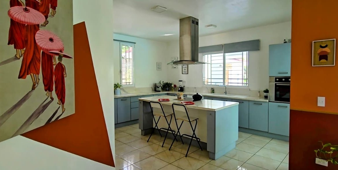 Cocina moderna con isla, sillas y paredes naranjas
