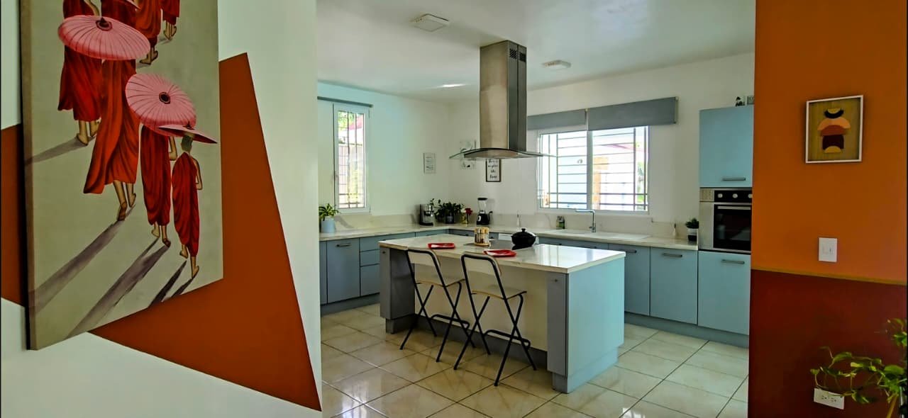 Villa en el limon (8) Cocina moderna con isla, sillas y paredes naranjas