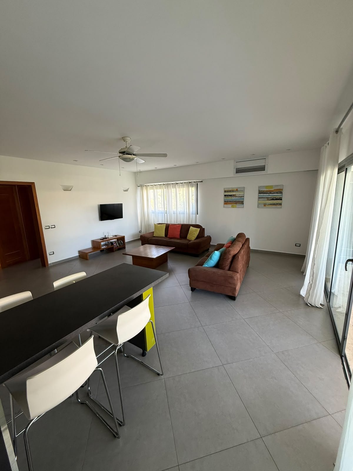 Apartamento Aligio (10) Salón comedor luminoso con sofás marrones y grandes ventanales