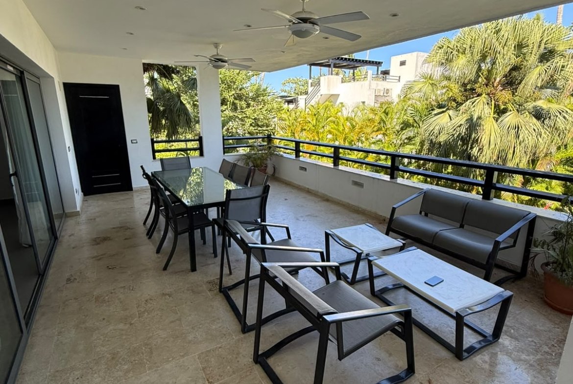Terraza cubierta con mobiliario moderno y palmeras