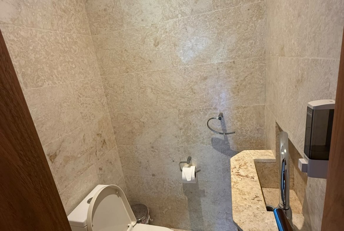Aseo compacto con revestimiento de piedra y ventana alta