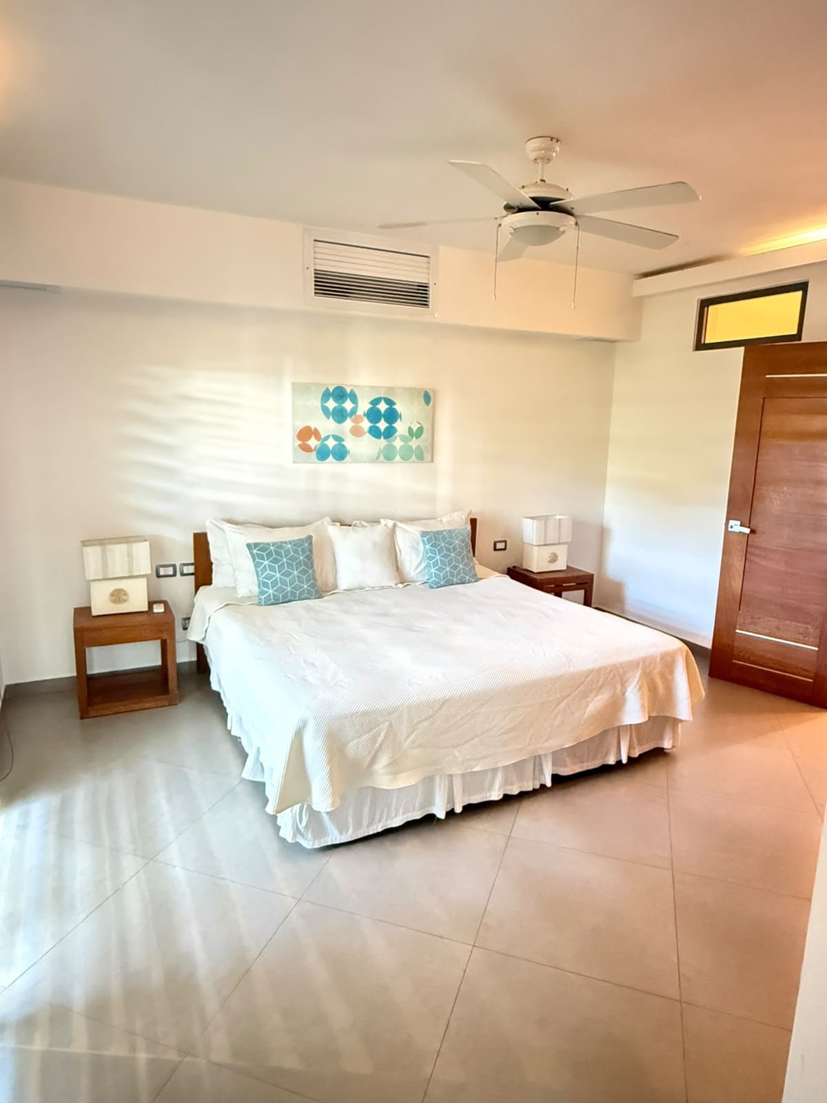 Apartamento Aligio (18) Dormitorio luminoso con cama doble, ventilador y mesillas