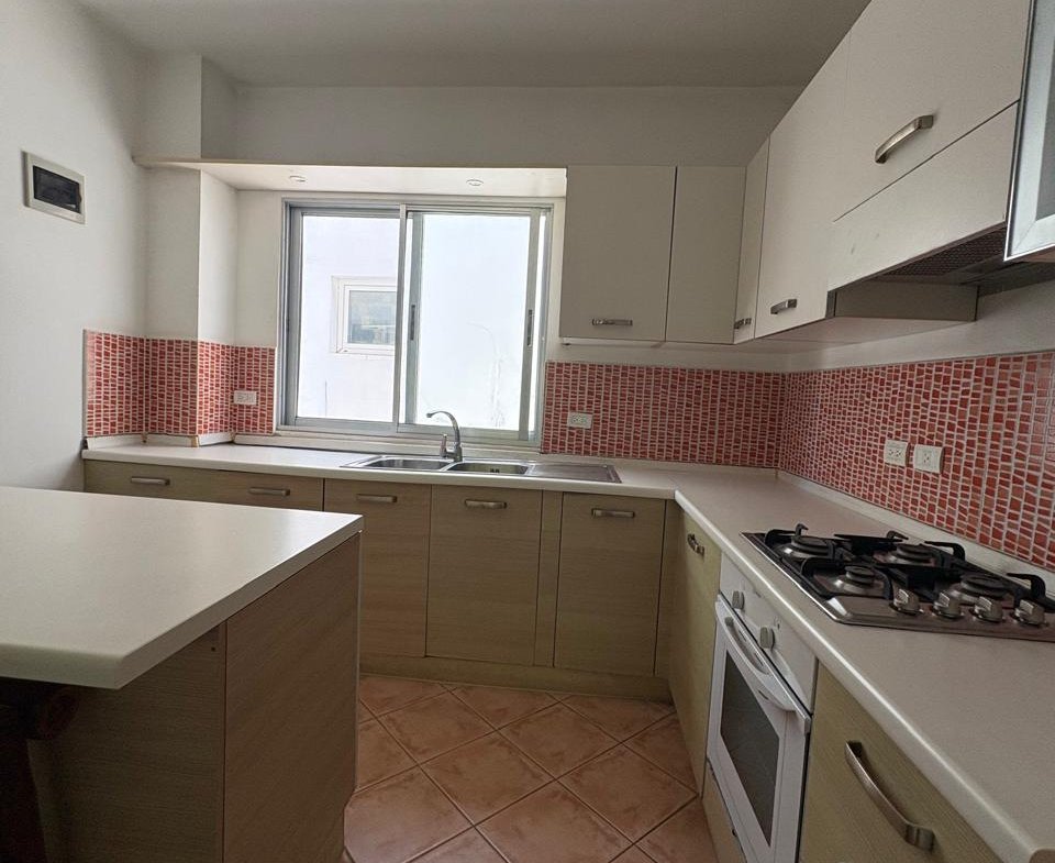 Cocina moderna compacta con muebles claros y azulejos rojos