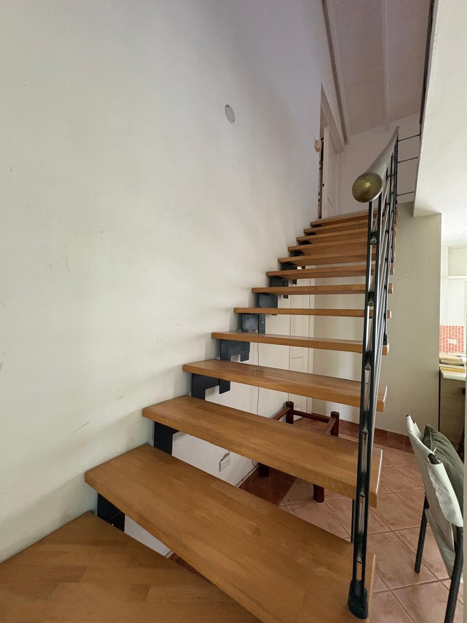 Apartemento Piattini (5) Escalera interior de madera con barandilla metálica negra