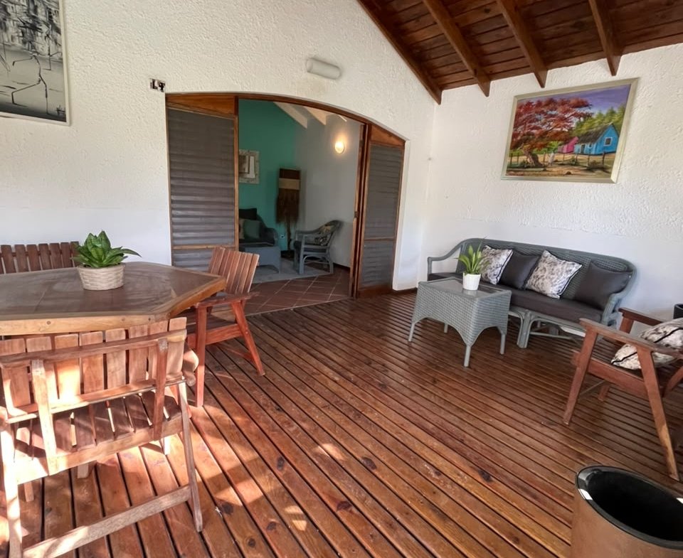 Véranda en bois avec salon, table et ventilateur plafond