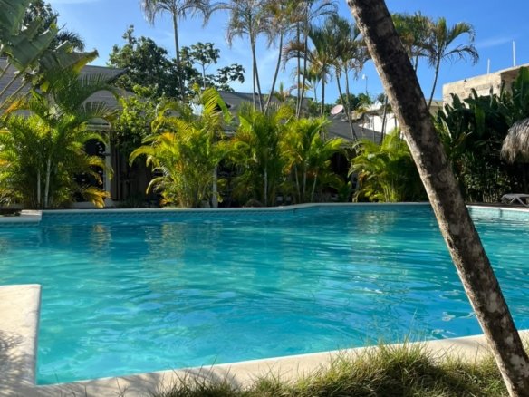 Piscina turchese circondata da palme sotto un cielo blu