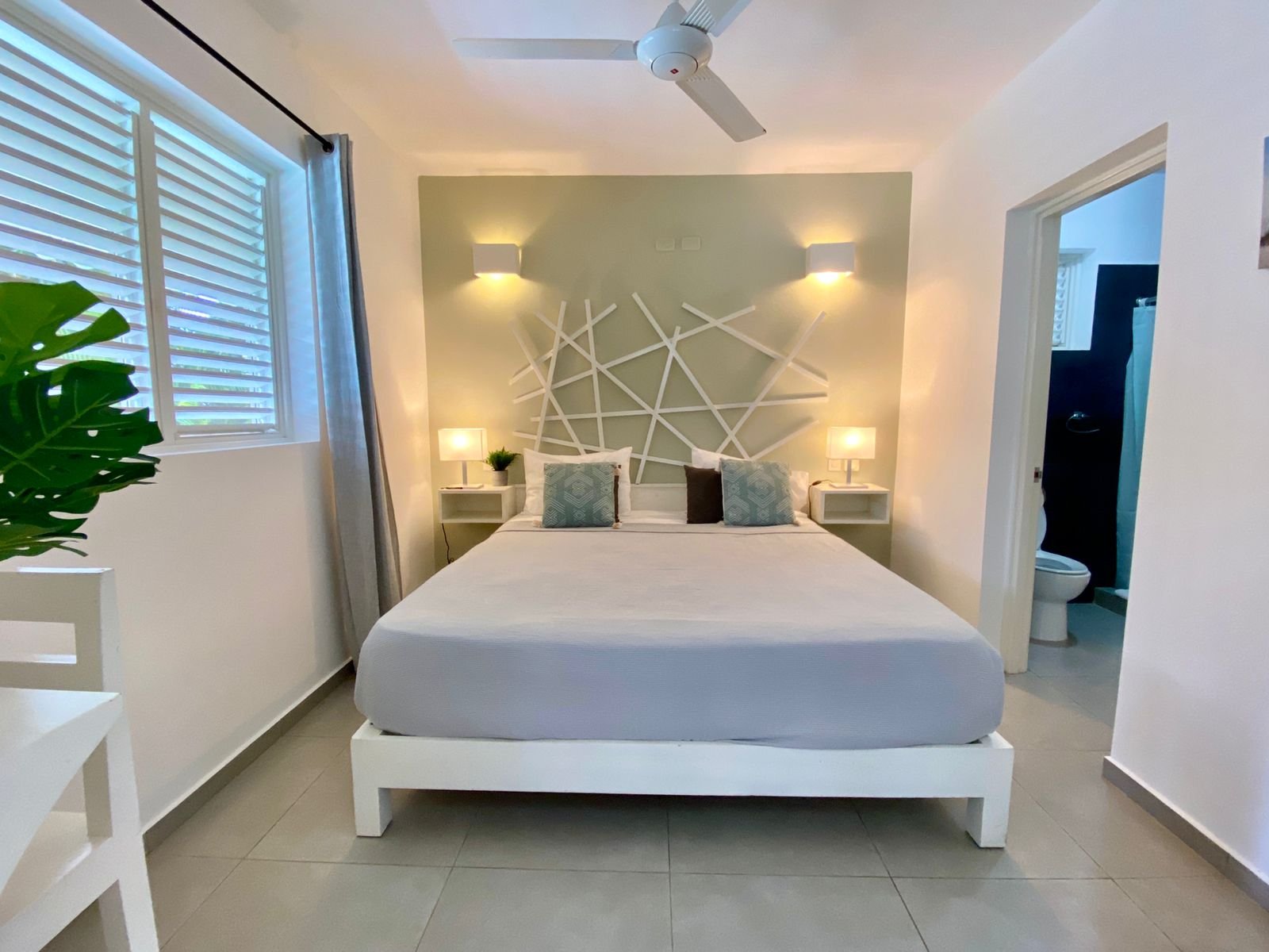 Dormitorio moderno con cama doble, iluminación cálida y baño
