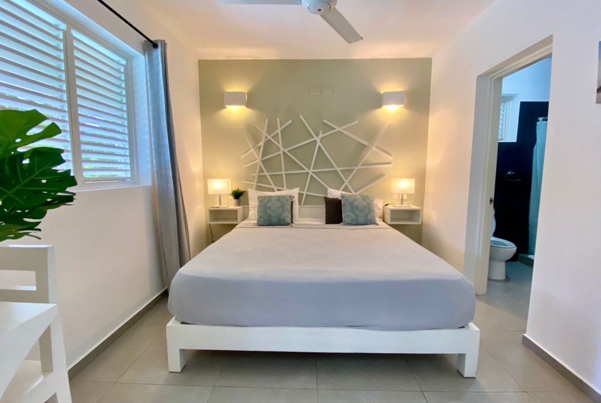 Dormitorio moderno con cama doble, lámparas y baño contiguo