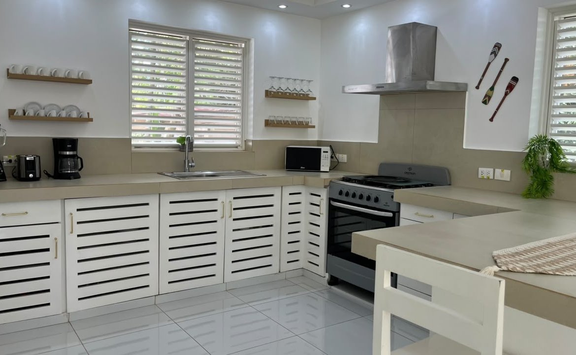Cocina blanca moderna con horno, isla y persianas