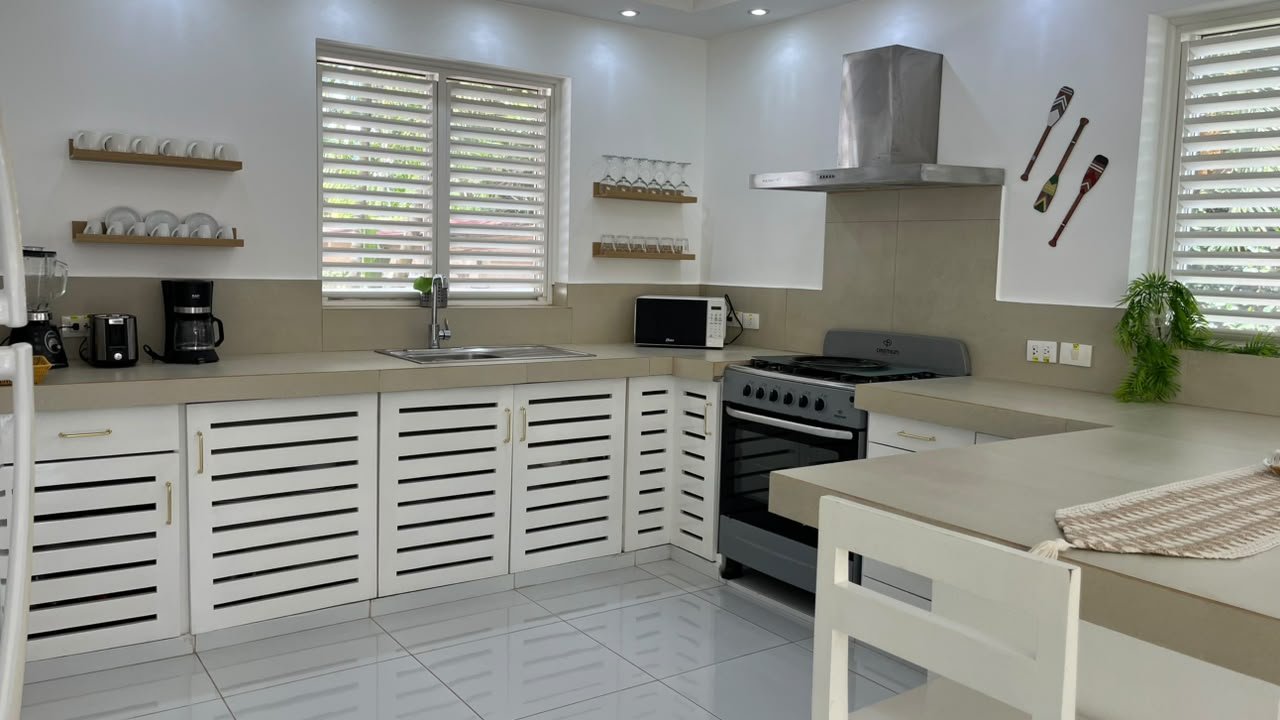 Cocina blanca moderna con horno, isla y persianas