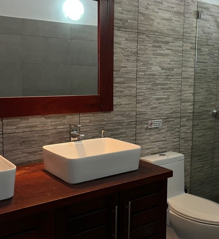 Baño moderno con lavabo sobre encimera y revestimiento gris