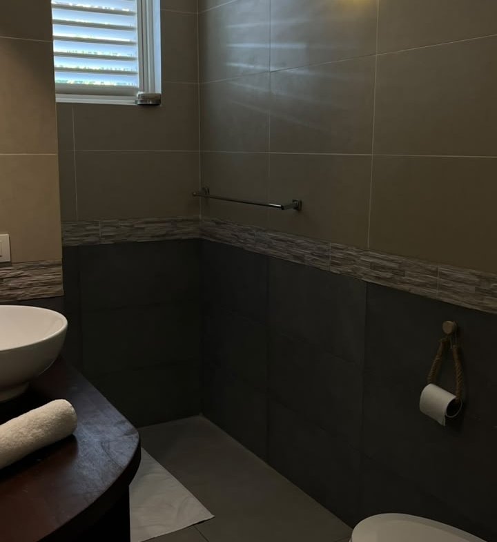Baño moderno con azulejos grises, lavabo y sanitario
