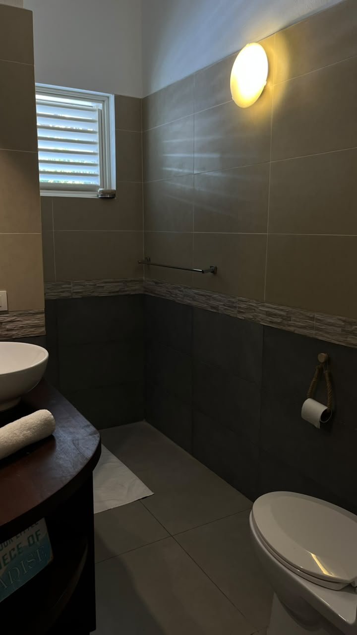 Baño moderno con azulejos grises, lavabo y sanitario