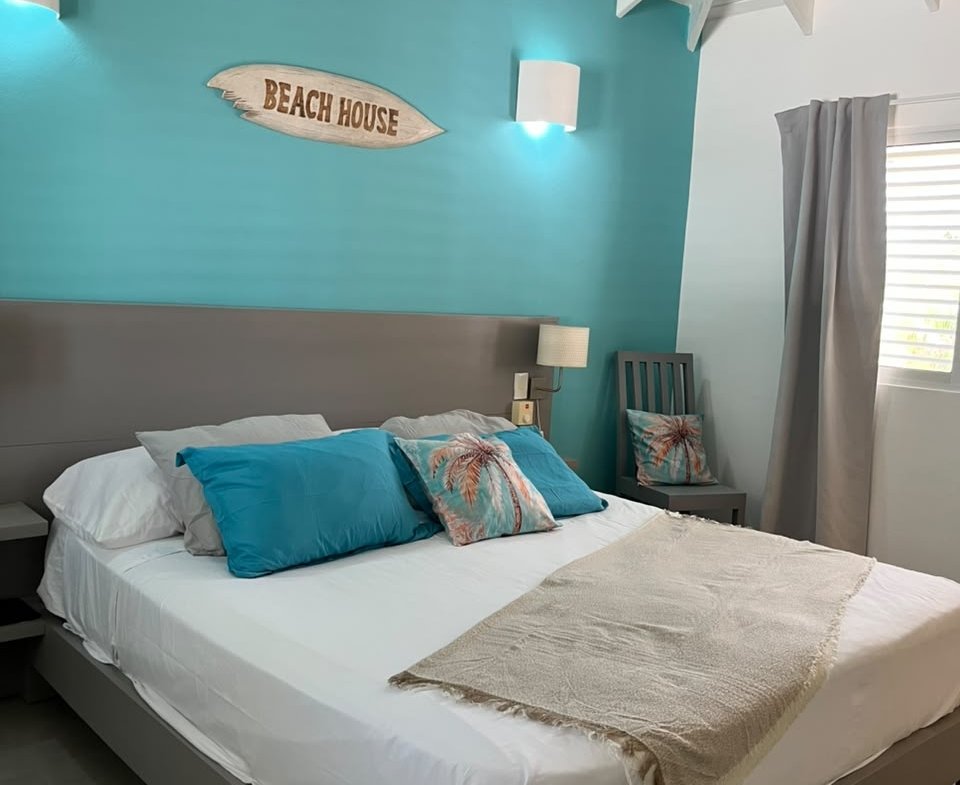 Dormitorio costero con cama blanca y pared turquesa