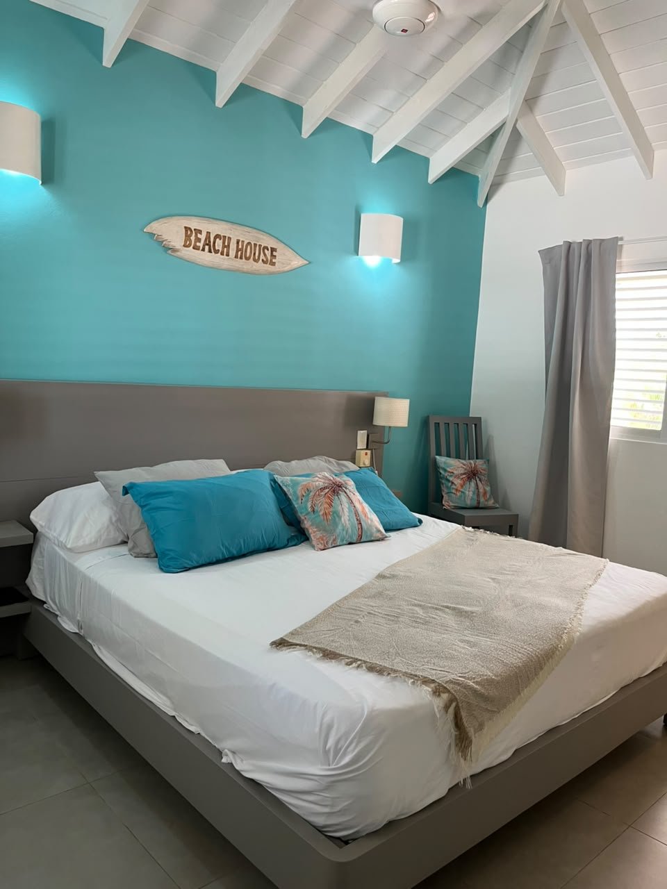 Dormitorio costero con cama blanca y pared turquesa