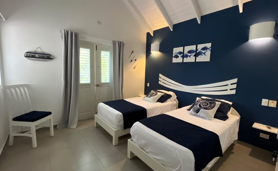 Dormitorio marinero con dos camas individuales y pared azul
