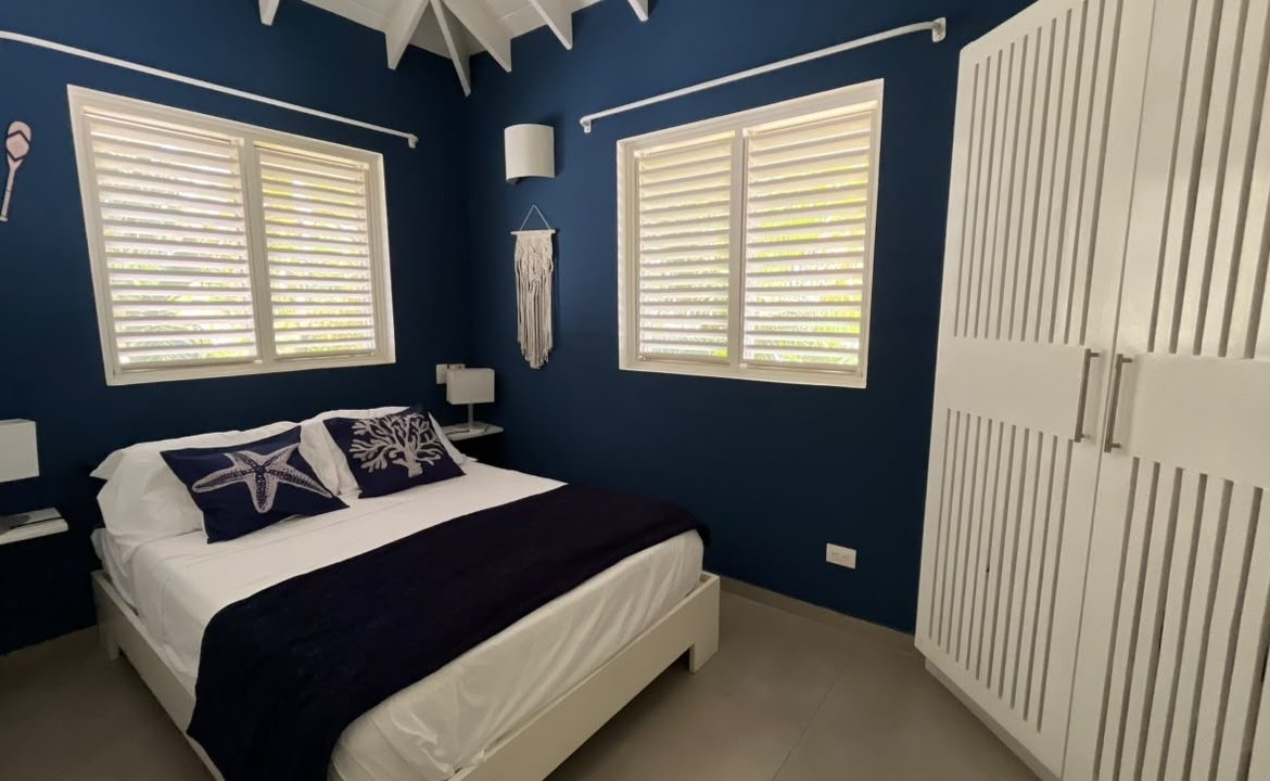 Dormitorio moderno azul marino con cama y armario blanco