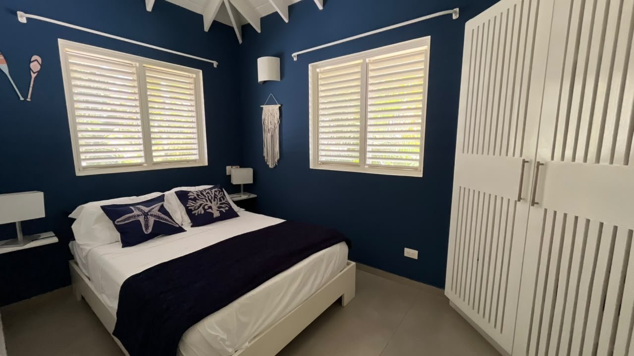 Dormitorio moderno azul marino con cama y armario blanco