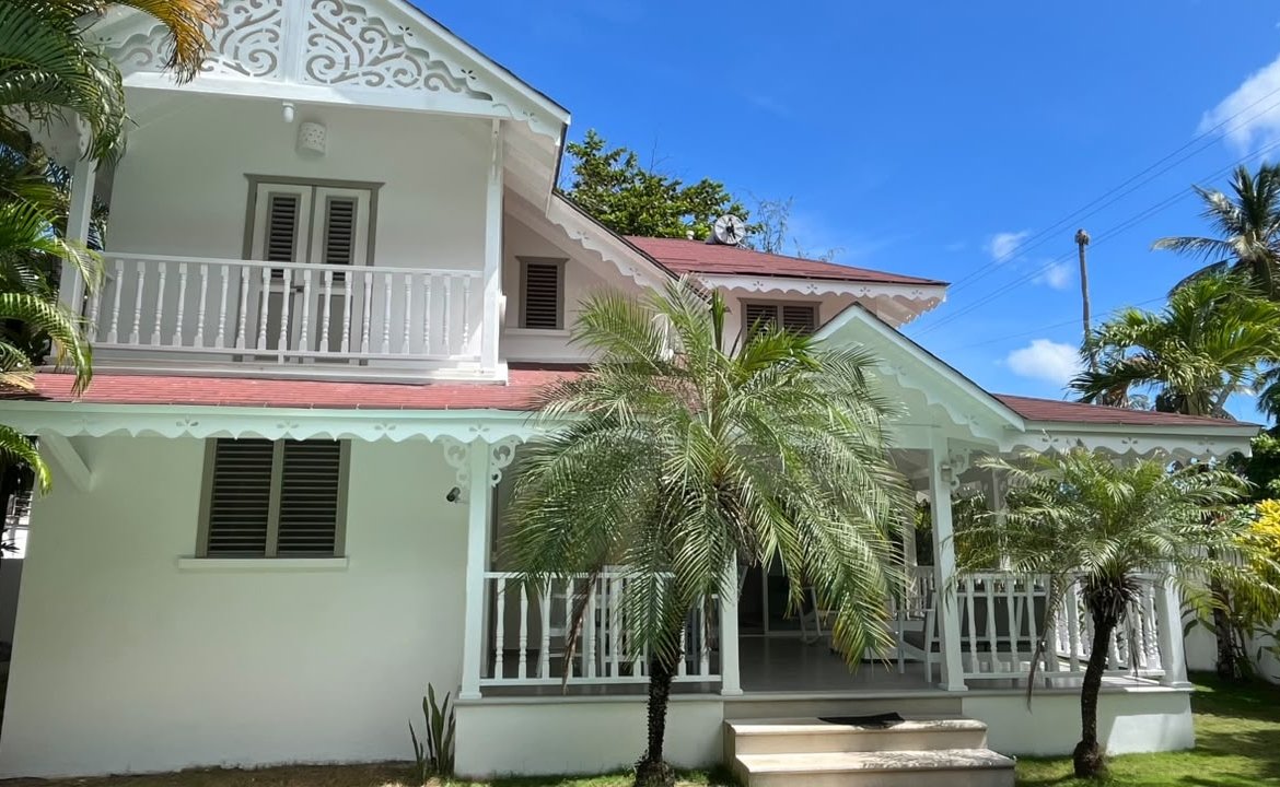 Casa blanca colonial con porche y palmeras tropicales