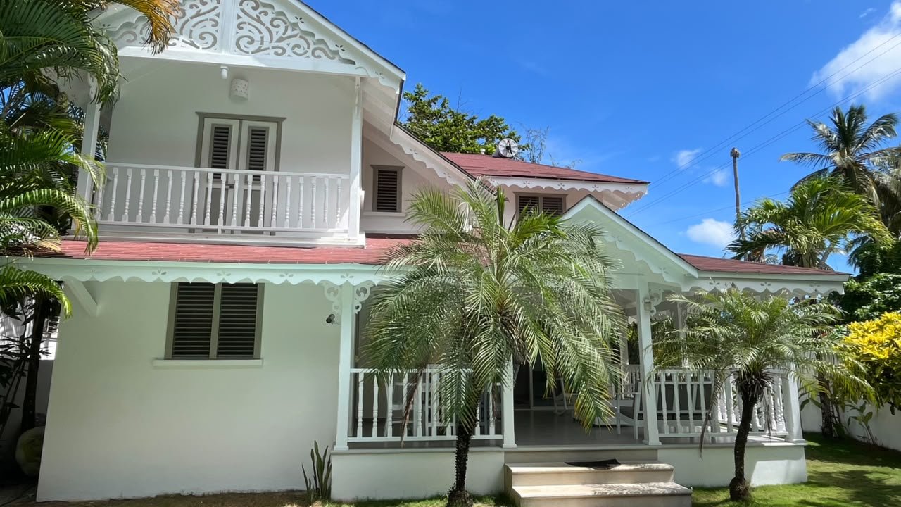 Casa blanca colonial con porche y palmeras tropicales